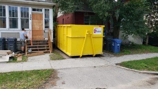 A large yellow and red garbage bin placed in a driveway